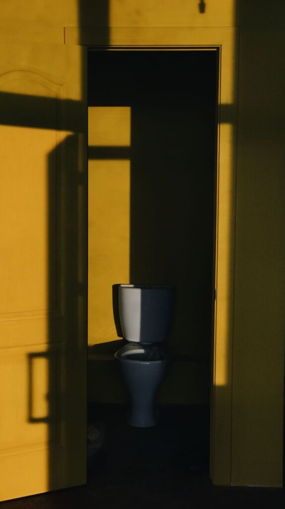 A minimalist restroom interior in bright yellow, showcasing intriguing shadow play on the walls.